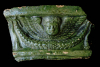 Fragment einer Gesimskachel mit geflügeltem Puttenkopf über lorbeerblattbesetztem Feston, grün glasiert, zweite Hälfte 17. Jh., H. 11,5 cm, Br. 20,0 cm, Baden-Baden Steinach, Museum