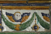 Fragment einer Gesimskachel mit geflügelten Puttenköpfen über lorbeerblattbesetzten Festons, mehrfarbig glasiert, 17. Jh., Innsbruck, Tiroler Volkskundemuseum