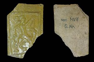 Fragment einer hängenden Kranzkachel vom Typ Tannenberg mit Samson als Löwenbezwinger gelb glasiert, letztes Drittel 14. Jh.; H. 12,0 cm, Br. 7,7 cm; Frankfurt a. Main, Historisches Museum (Inv.-Nr. X 2009.815), urspr. Frankfurt a. Main (?)